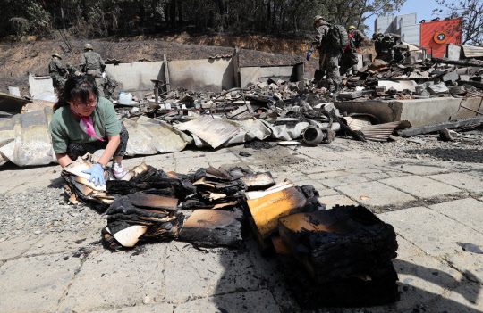 7일 산불로 가옥이 불에 탄 강원 강릉시 홍제동의 한 주민이 흔적만 남은 집터에서 꺼낸 불에 그슬린 족보를 보며 안타까워하고 있다.